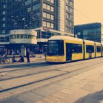 Selective color photography of yellow train near concrete buildings