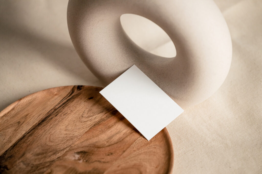 Minimalist still life with white sculpture wooden plate and plain card